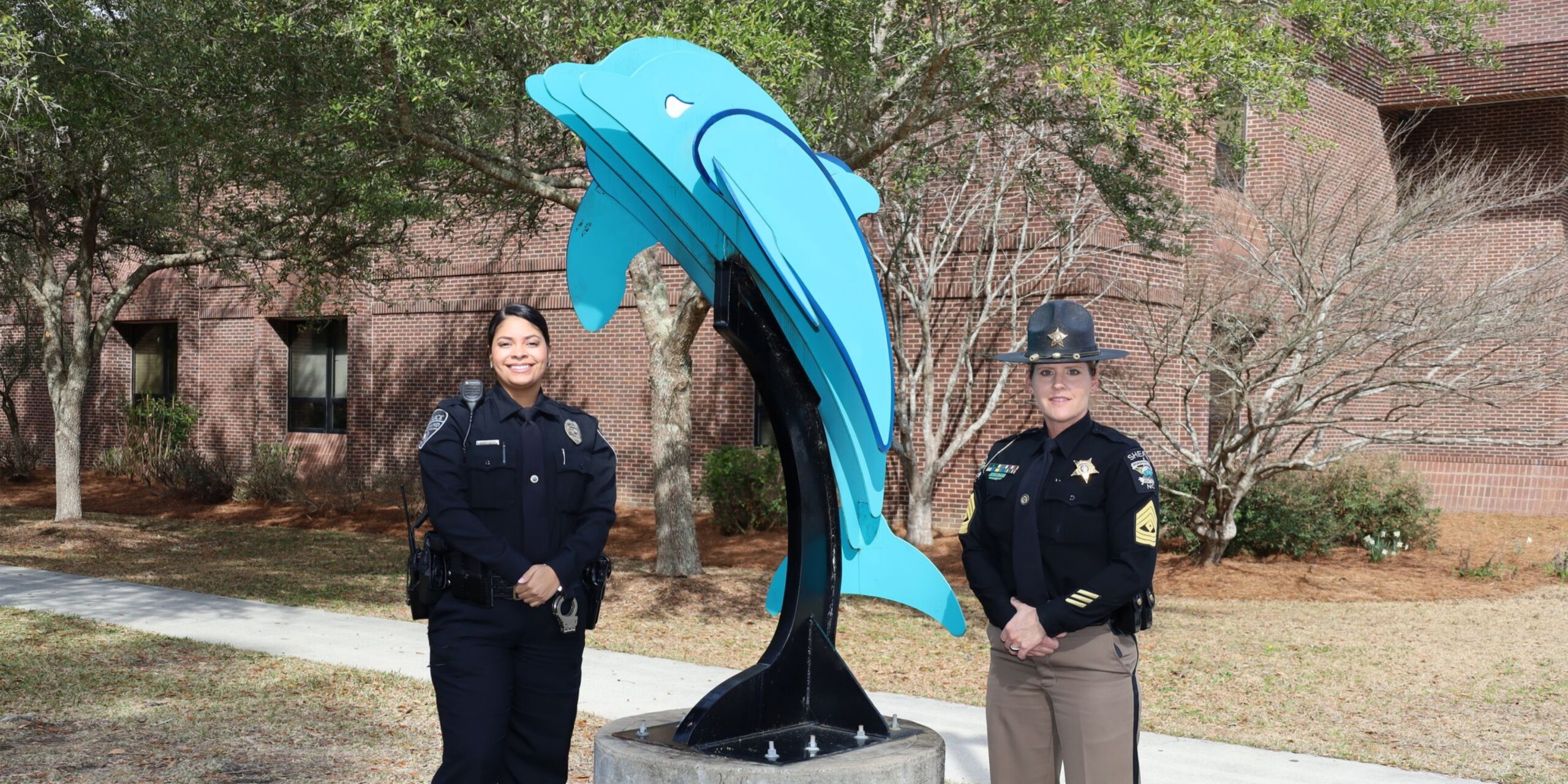 two law enforcement officers standing near dolphin statue