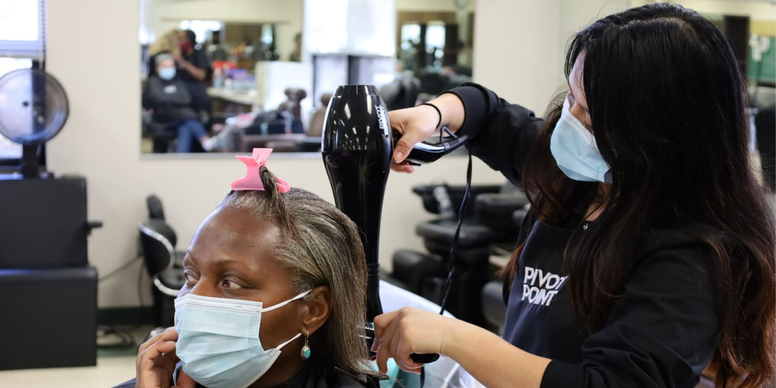 cosmetology student blow drying a client's hair